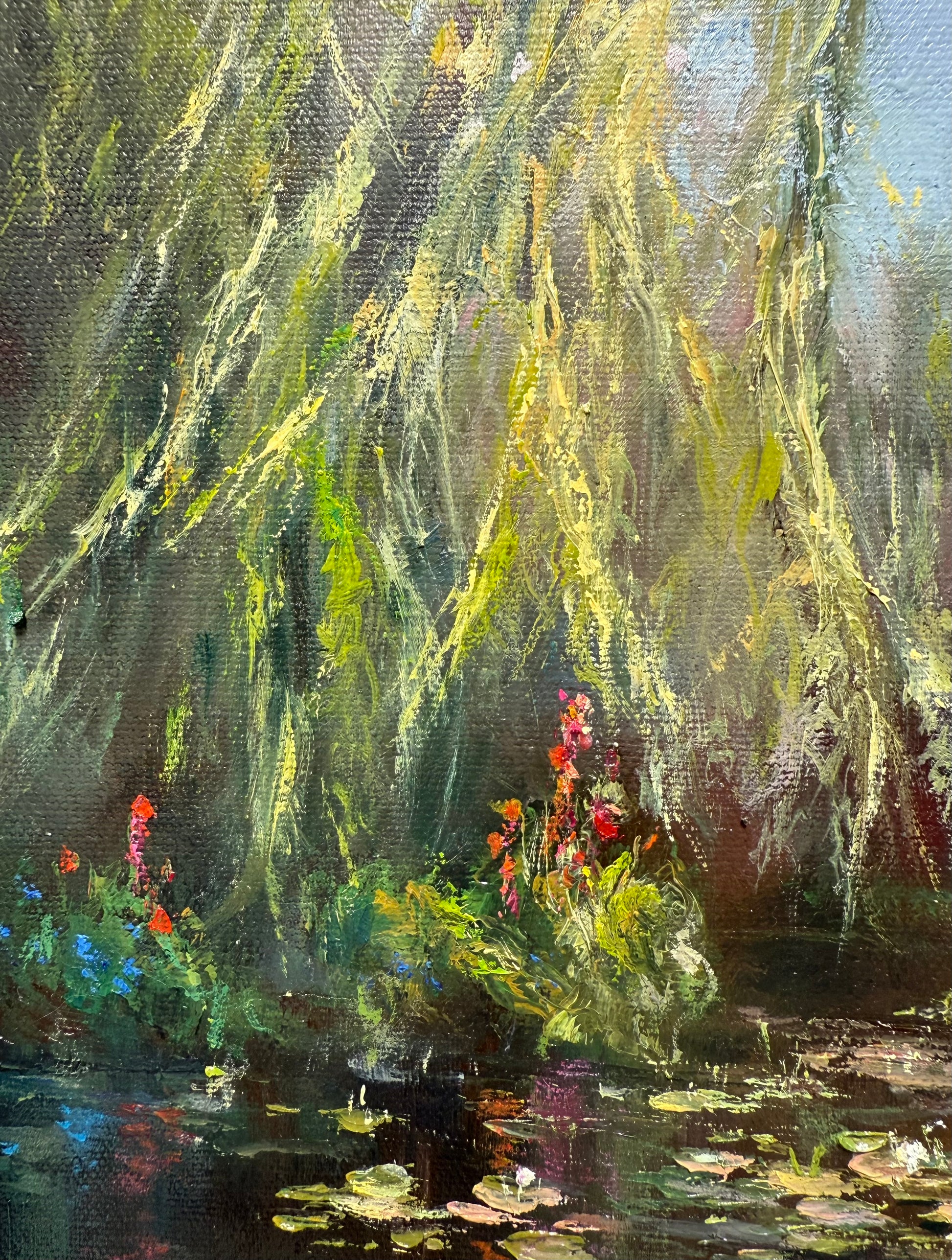 Close up of a willow tree branches hanging above the lily pond.