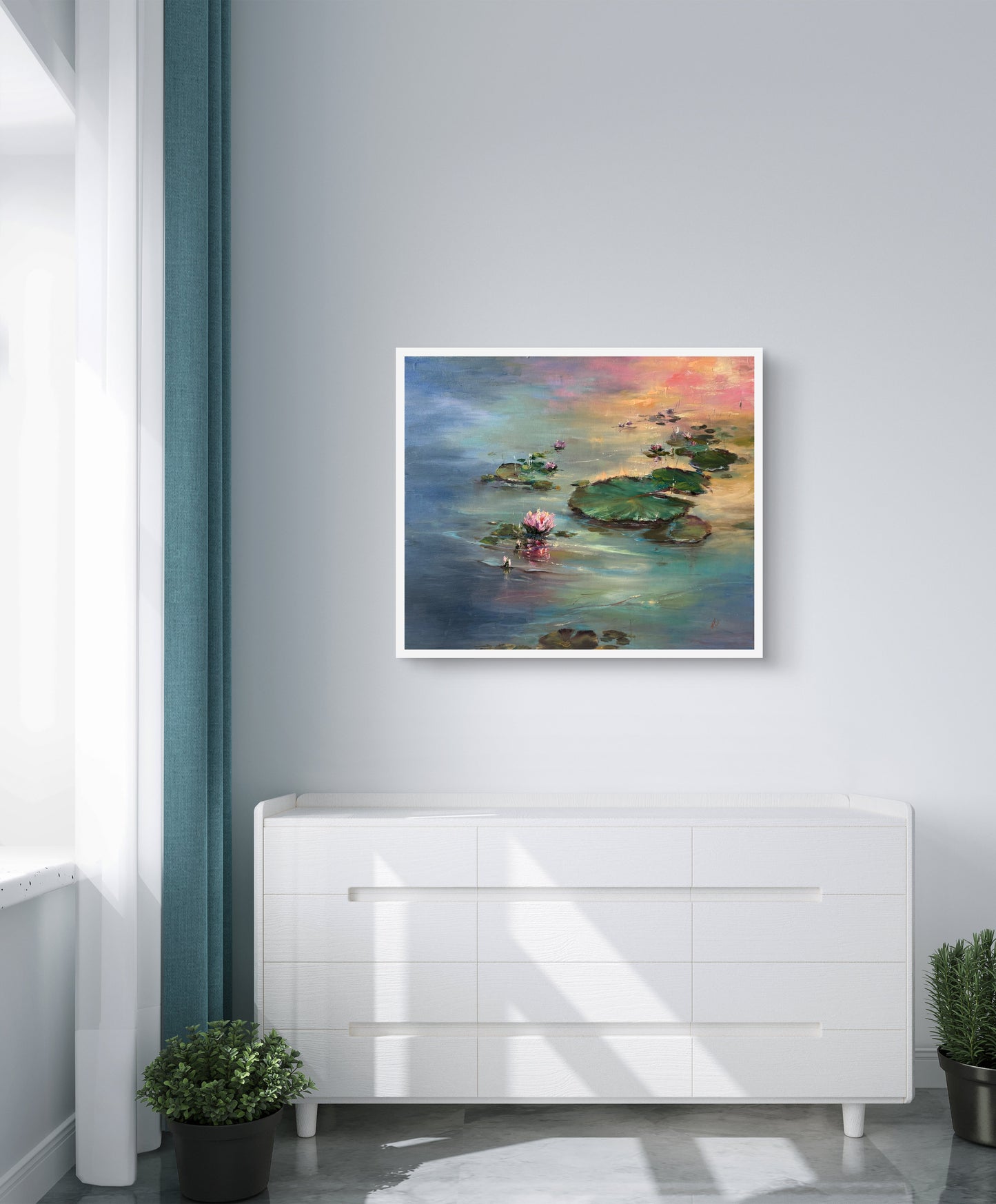 Framed painting of a lily pond on a wall above a white cabinet.