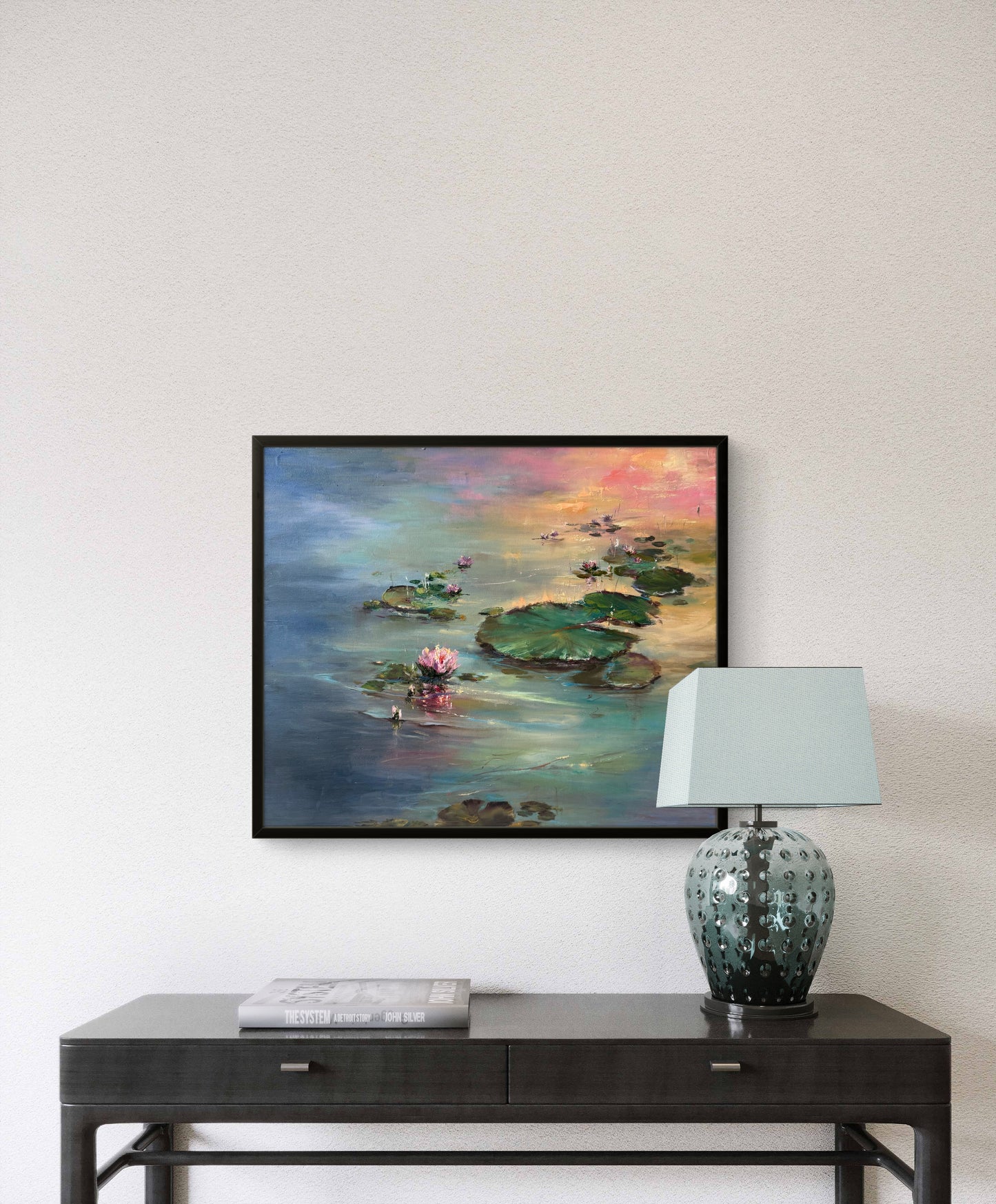 Framed painting of a water lily on a wall above a side table.