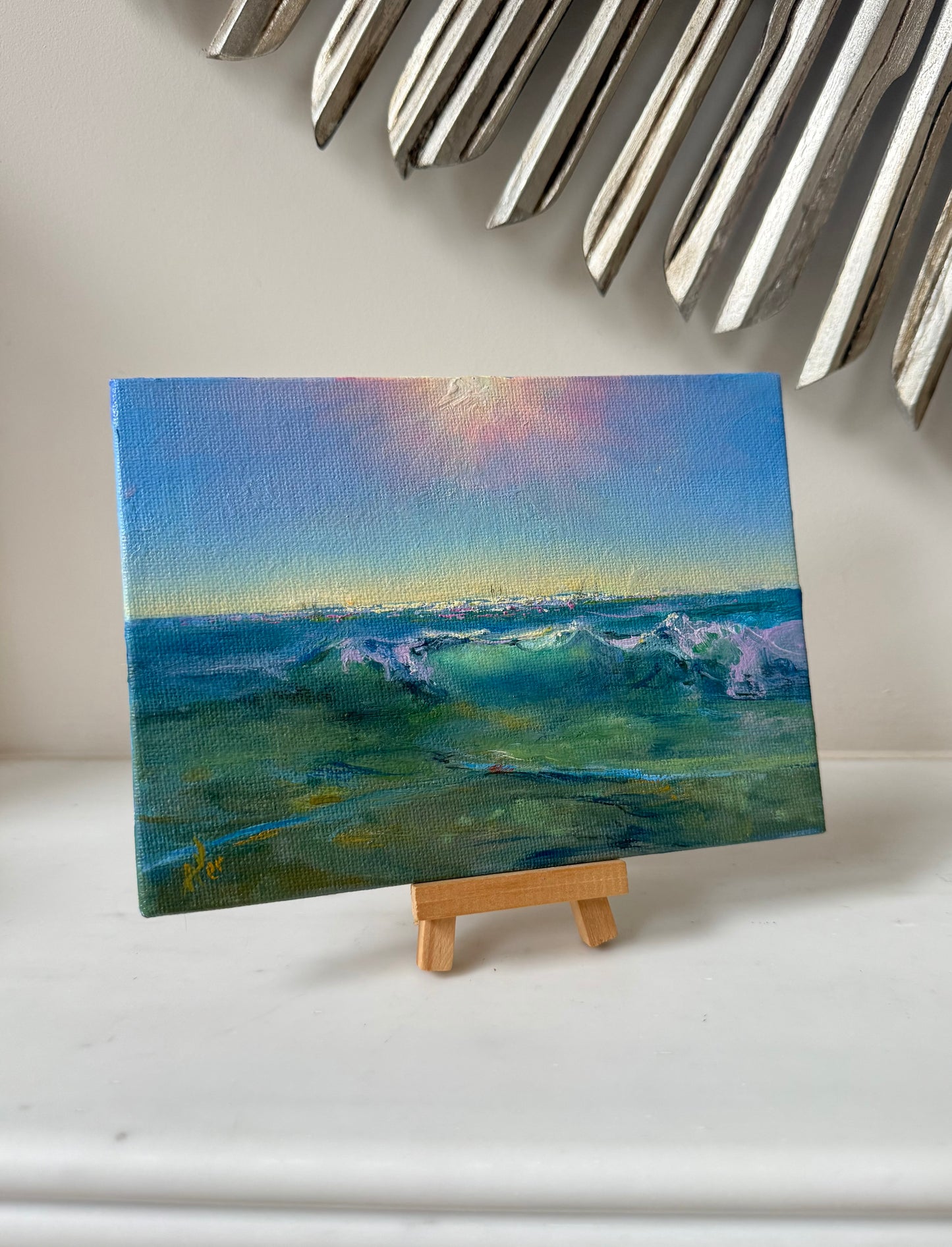 Ocean painting, showing green waves, clear shallow waters, sunlight and sail boats at the distance.