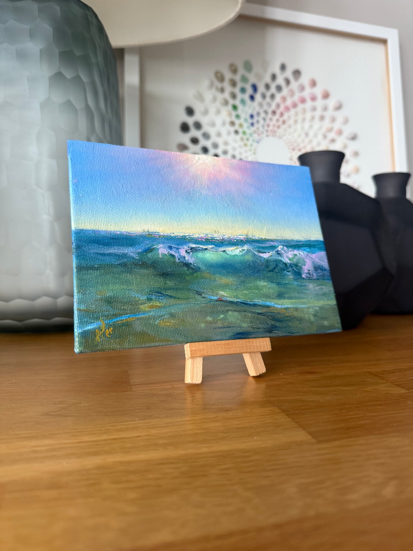 Small seascape on a small wooden easel, showing green clear seawaters on a sunny day.
