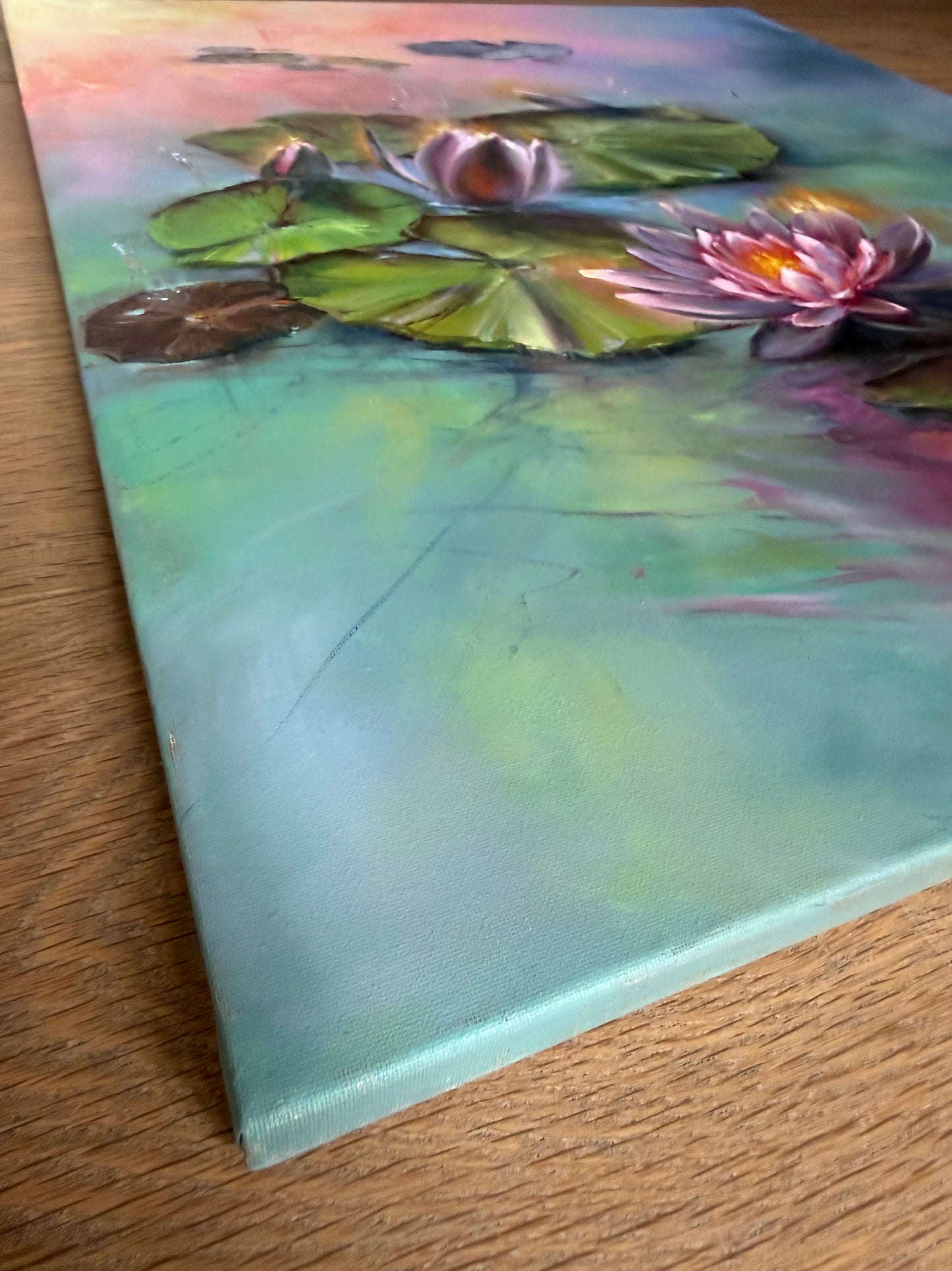Painting of water lilies on a canvas, painted on sides. The water is teal with sunrise reflections. 
