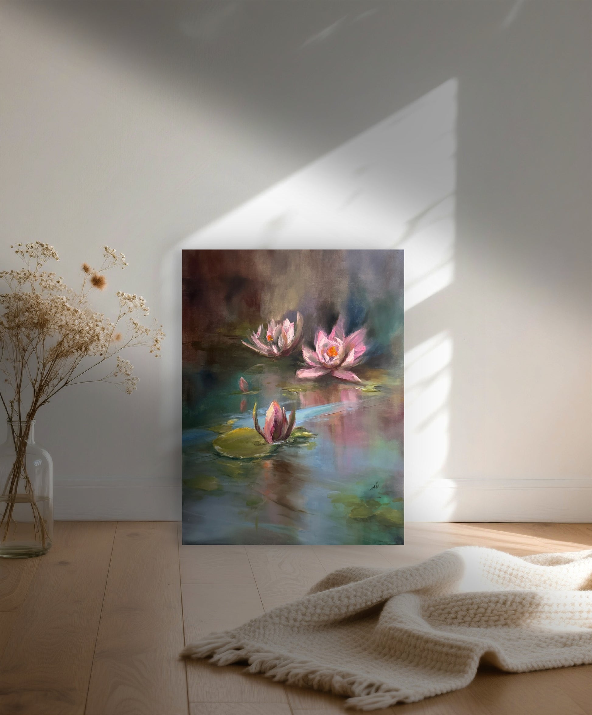 Painting of a lily pond with pink water lilies on a wall in a room with a vase of flowers and a blanket.