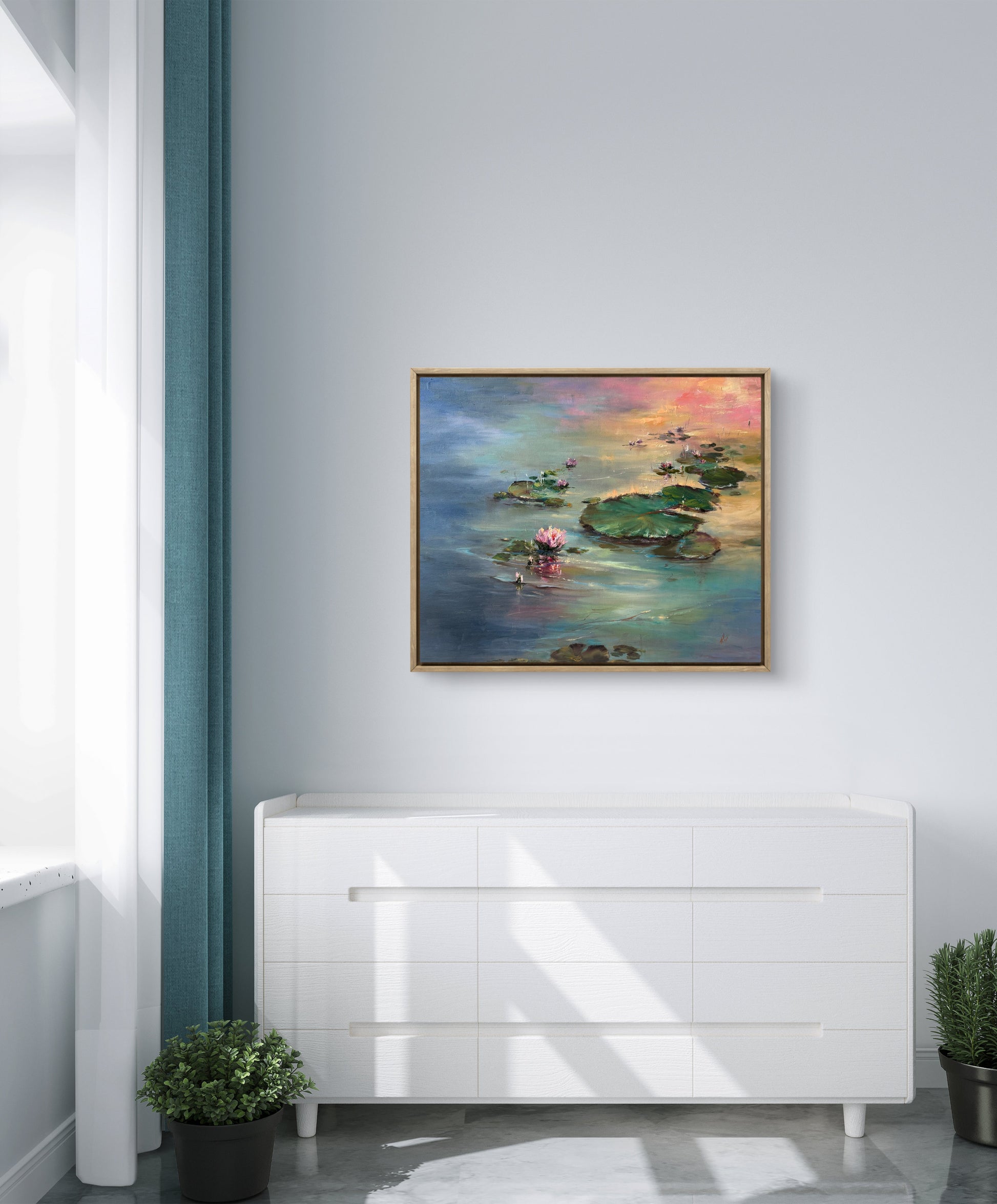 Framed painting of a lily pond hanging above a white cabinet.