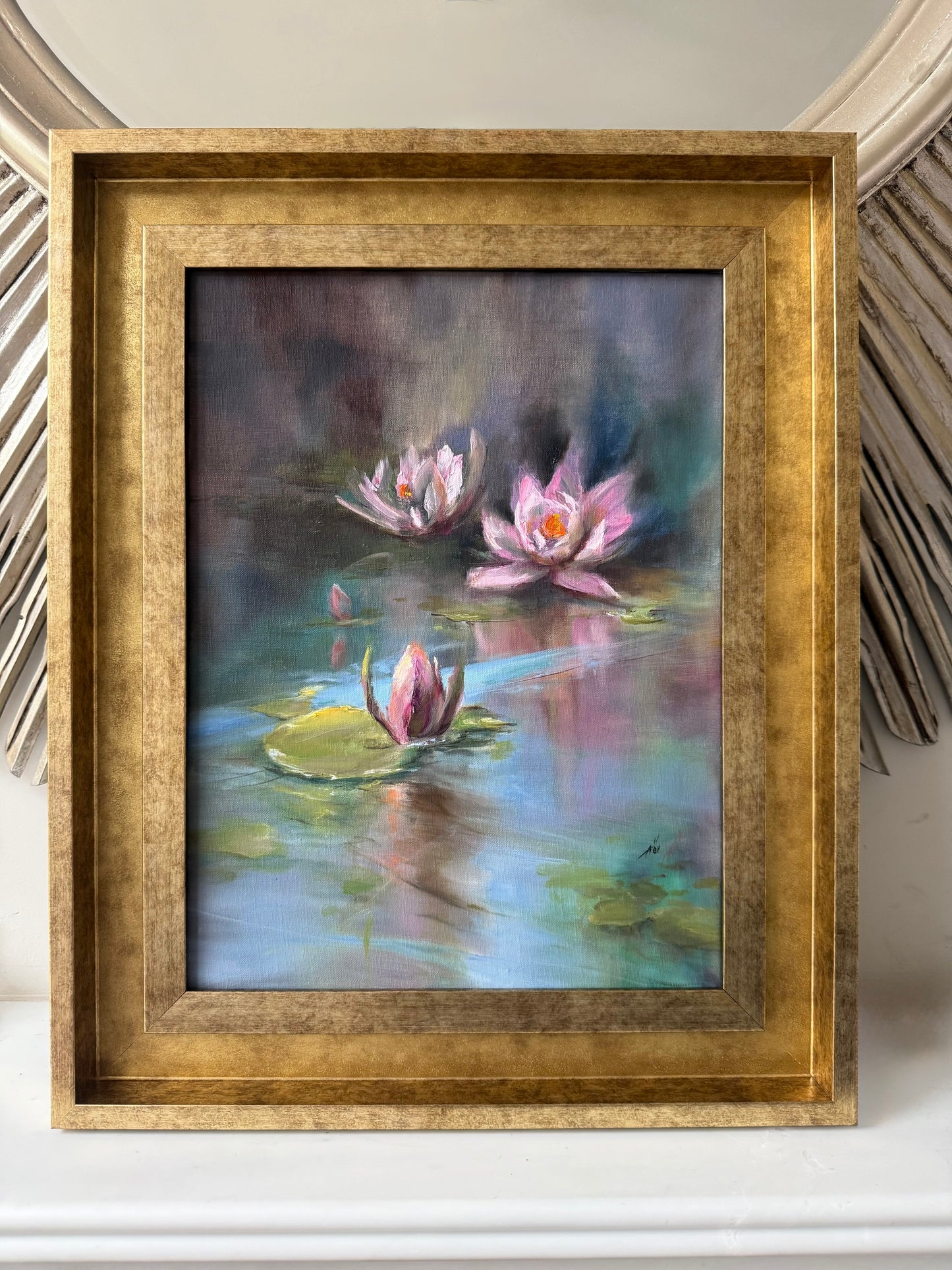 Framed painting of water lilies on a reflective pond surface