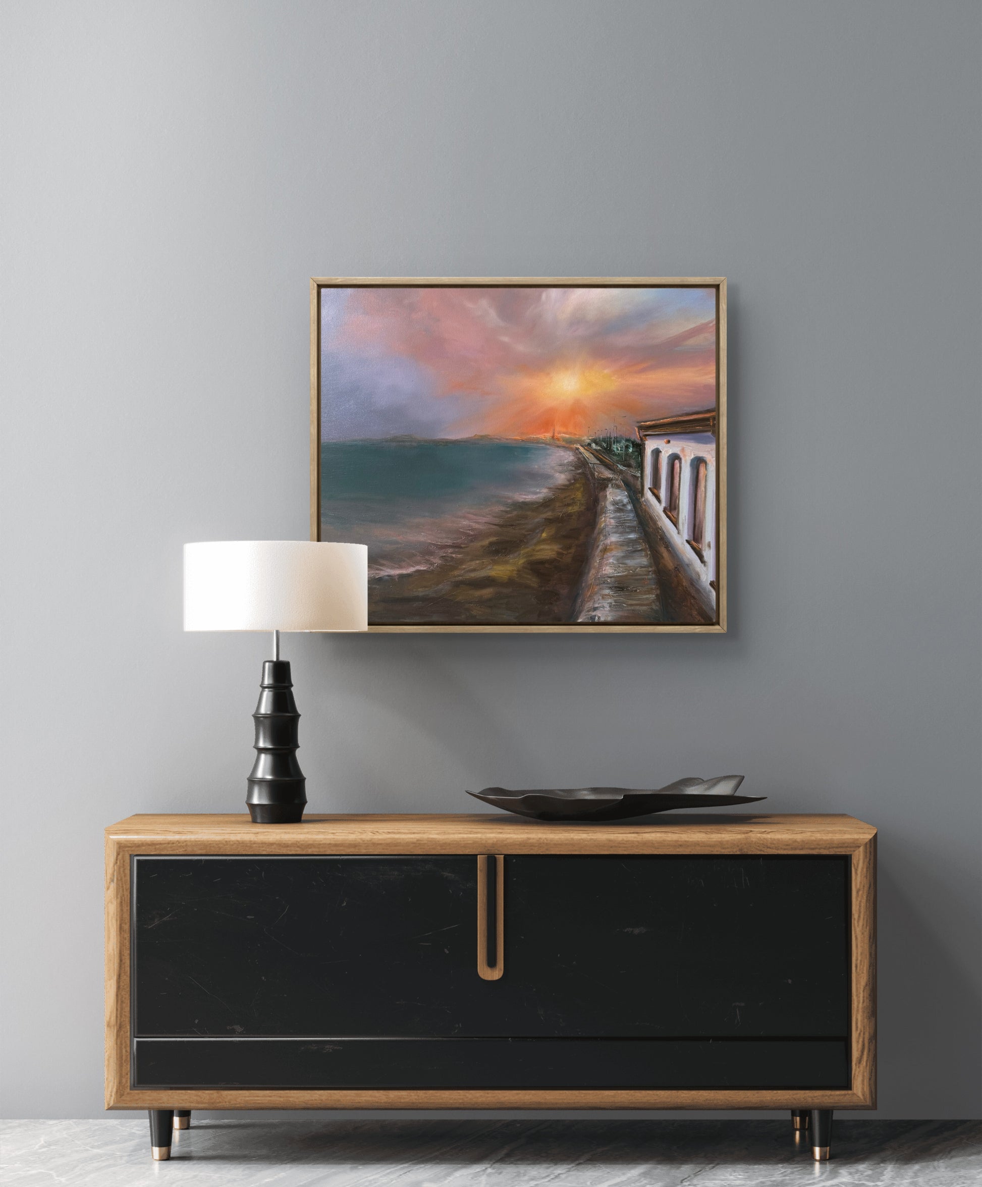 Seascape at sunset featuring beach cafe, framed and hanging on the wall above chest of drawers.